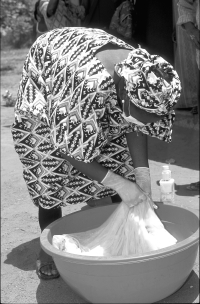 Clinic worker in Kiyi Village showing villagers how to soak a bed net in insect repellant.