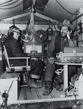 Robert Taylor listens in with sound technician Howard Voss in the special Sound Truck while on location for MGM's Westward the Women (1951).