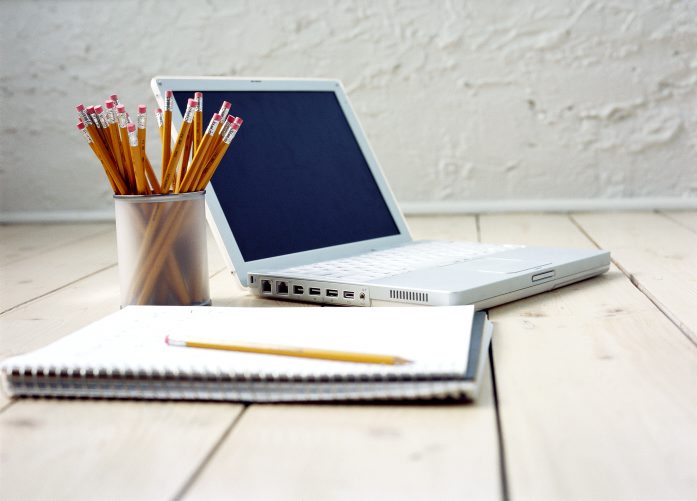 picture of computer and notebook used to write a research paper