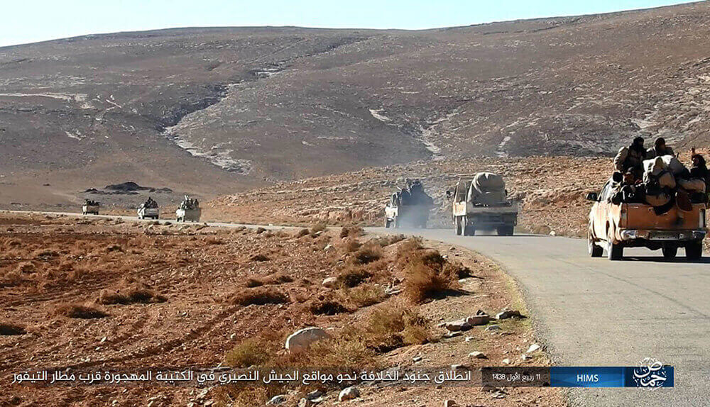 Image of man placing wreath onto memorial for those killed in Palmyra