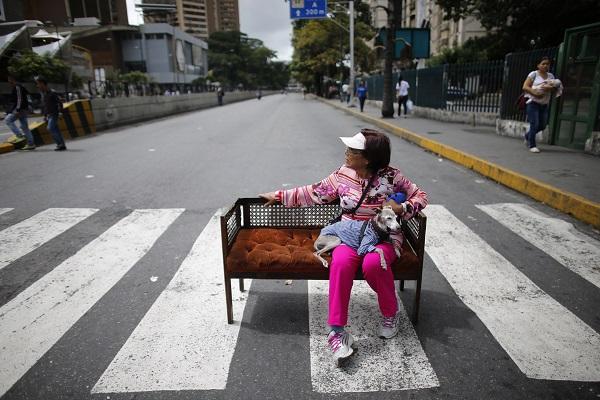 Woman and her dog sit on a couch blocking the street